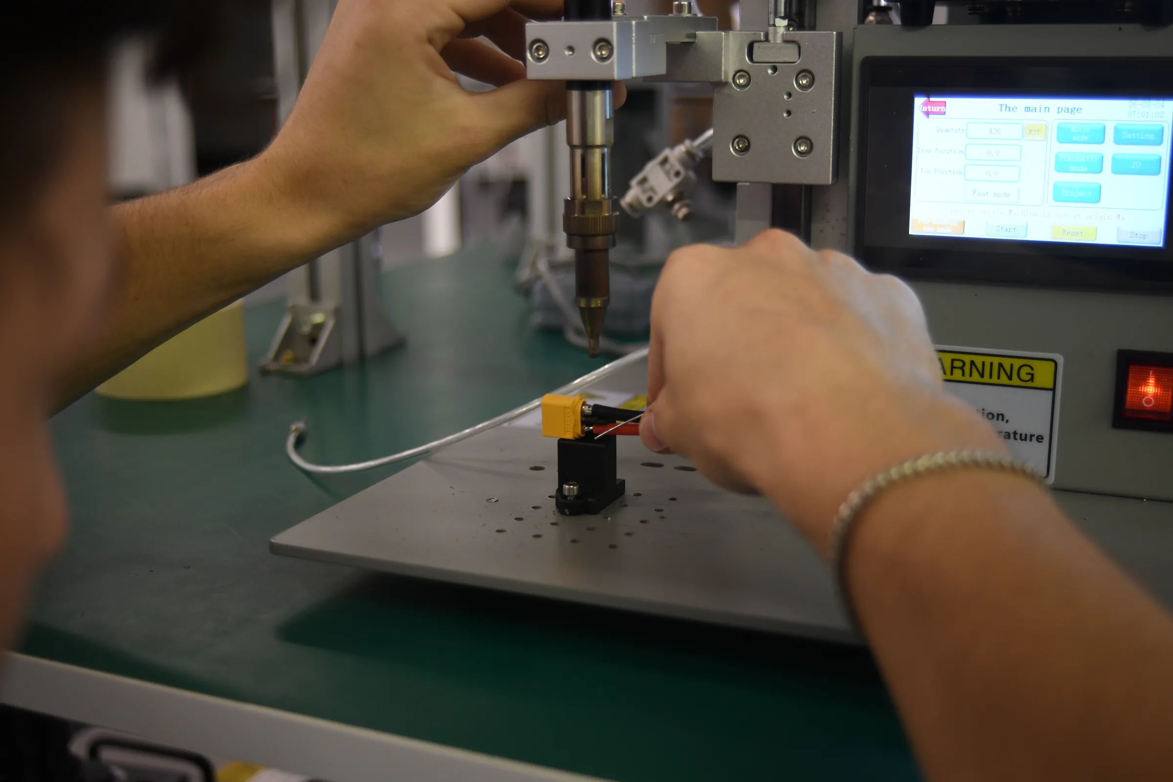 A technician using a benchtop dispensing machine on a component at the Unmanned Industries facility