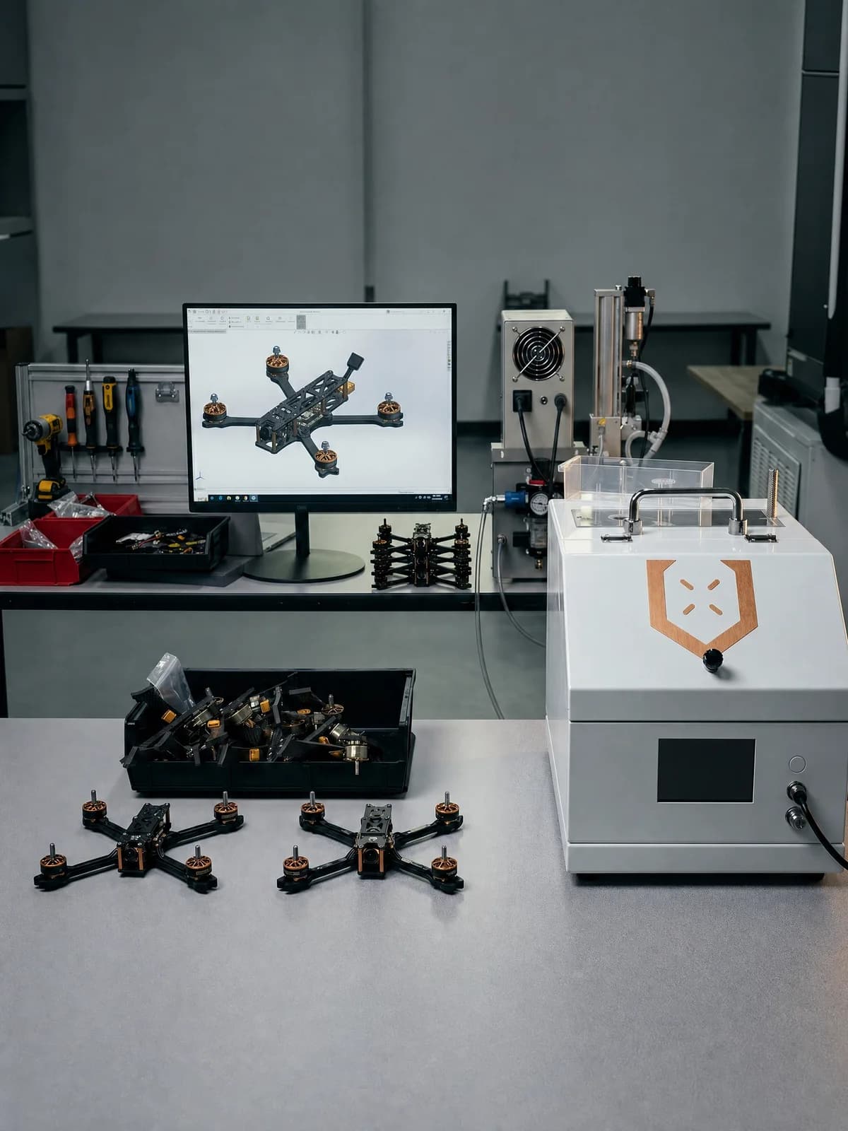 Assembly bench with finished FPV drones, a CAD workstation, and hand tools in the Unmanned Industries facility
