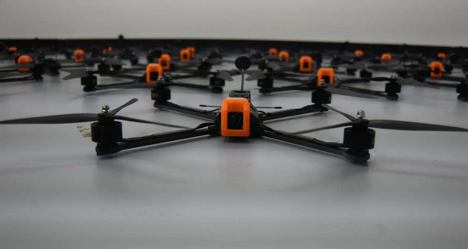 Unmanned Industries T100 FPV airframes, head-on view zoomed in on the foreground unit with a full production line behind it