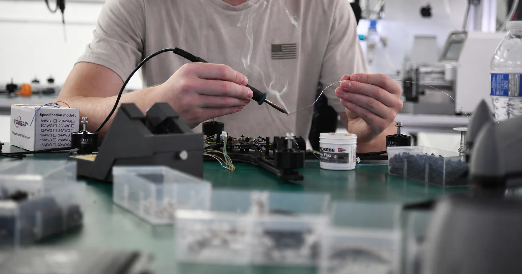 An Unmanned Industries technician hand-soldering a motor assembly at the workbench